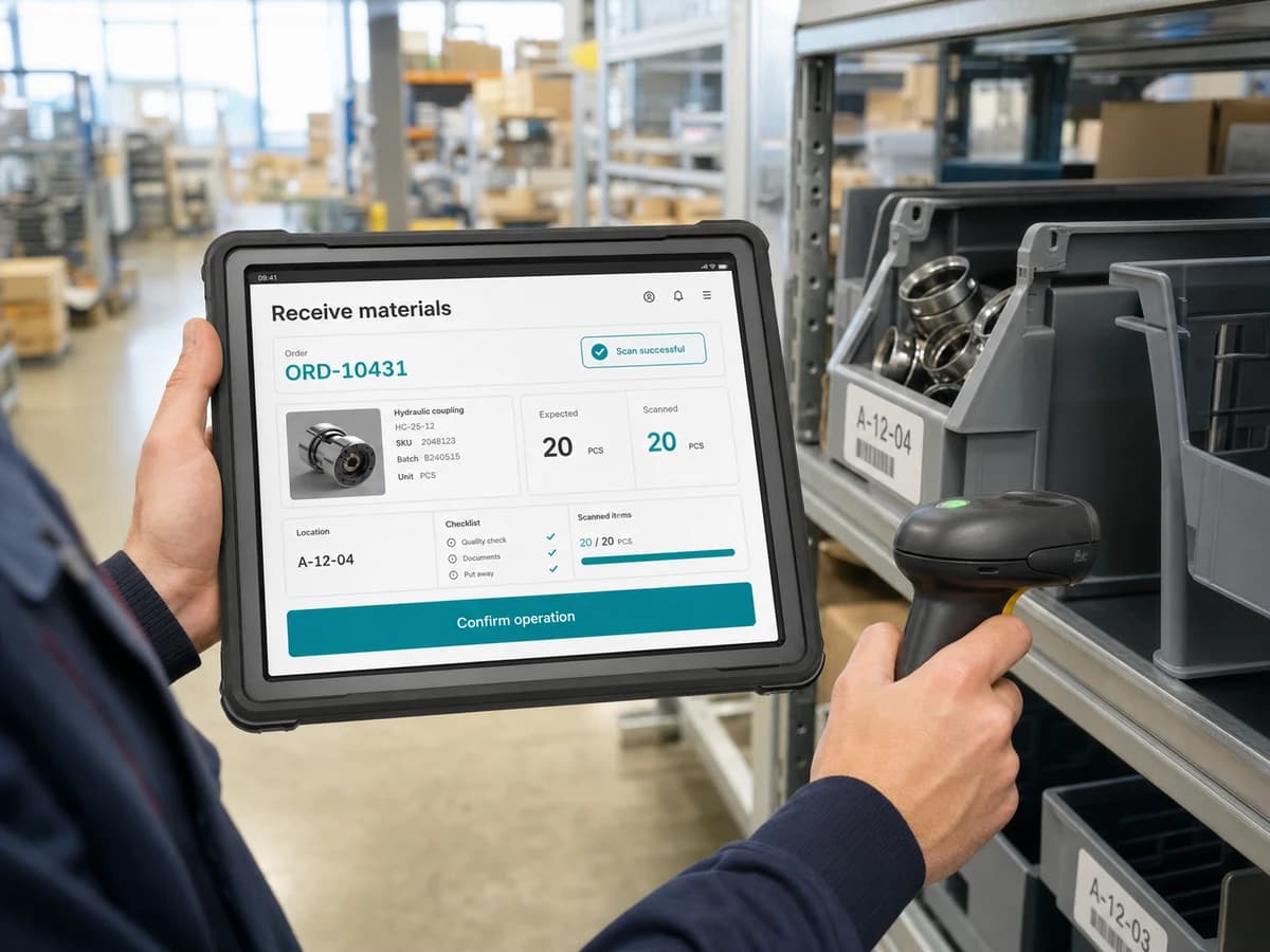 A worker using a tablet and scanner in a warehouse or production area to confirm an operation.